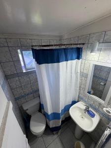 ein Badezimmer mit Waschbecken, Toilette und Duschvorhang in der Unterkunft Cabaña Pichidangui in Pichidangui