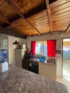 eine Küche mit roten Vorhängen und einer Arbeitsplatte in der Unterkunft Cabaña Pichidangui in Pichidangui