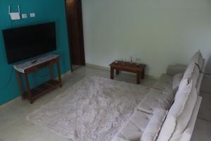 a living room with a white couch and a flat screen tv at sunshine home in Paraty