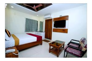 a bedroom with a bed and a chair and a phone at HOTEL THANVI iNN in Guntūr