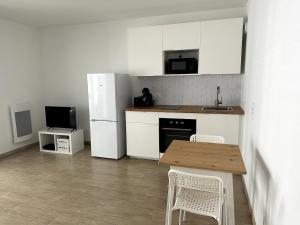 a kitchen with a wooden table and a white refrigerator at Studio Récent Prés d'Arènes Terrasse Wifi parking privé in Montpellier