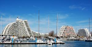 a large white building next to a marina with boats at Studio Récent Prés d'Arènes Terrasse Wifi parking privé in Montpellier