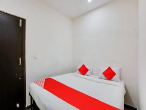 a bedroom with a white bed with red pillows at Hotel O Manjushree Boarding & Lodging nearby Dr.BR Ambedkar Stadium Basveshwar nagar in Bengaluru