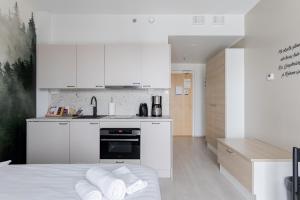 a kitchen with white cabinets and a bed in a room at Hotelli Kuohu Kangasala - Hotel and Apartments by UHANDA in Kangasala