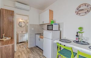 a small kitchen with a table and a white refrigerator at Awesome Home In Potomje With Wifi in Potomje