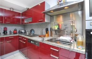 a red kitchen with a sink and red cabinets at Awesome Apartment In Cagnes-Sur-Mer in Cagnes-sur-Mer