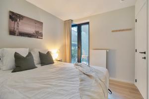 a bedroom with a white bed and a large window at Premium Holidays - New design flat near the beach of Nieuwpoort in Nieuwpoort
