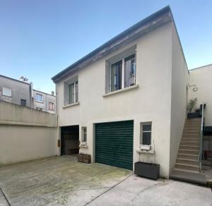 a white house with a green garage door at Le Traverse élégant T2 au cœur du centre ville in Brest