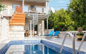 ein Pool mit blauen Stühlen und ein Haus in der Unterkunft 3 Bedroom Stunning Home In Podstrana in Podstrana + 20 Fotos
