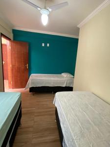 a room with two beds and a blue wall at Pousada Estrela Mares 307 in Cabo Frio