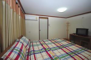 a bedroom with a bed and a television in it at Phoonsab Hostel in Phitsanulok