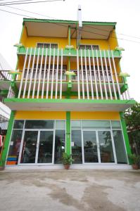 a yellow and green building with large windows at Phoonsab Hostel in Phitsanulok