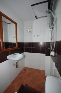 uma casa de banho com um lavatório, um espelho e um WC. em Phoonsab Hostel em Phitsanulok