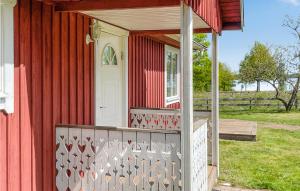 a red house with a porch with a white fence at Amazing Home In Vittaryd With Wifi in Kvänarp