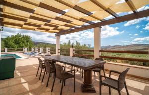 a wooden table and chairs on a patio with a pool at Lovely Home In Periana in Periana
