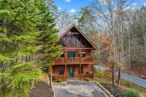 a log cabin in the woods with a driveway at NewListing 1mile Parkway, GameRoom, HotTub, BBQ, Sleeps 14, 5 Bedroom with attached Bath, PET Friendly in Pigeon Forge