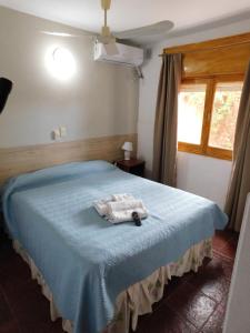 a bedroom with a blue bed with a towel on it at Hotel Posada Del Lago in Villa Carlos Paz