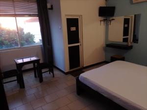 una camera da letto con un letto, un tavolo e una finestra di Akira Beach Hotel a Moratuwa