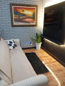 a living room with a couch and a flat screen tv at Lindo Loft na Praia dos Sonhos in Itanhaém
