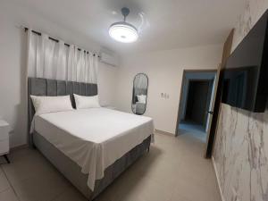 a bedroom with a white bed and a mirror at Comfortable apartment in Los Mameyes