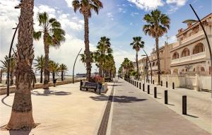 a street with palm trees and a bench on a beach at Stunning Apartment In Santa Pola in Santa Pola