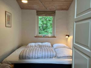 a bed in a small room with a window at Cosy Summer Cottage Glose To Sandy Beach! in Knebel