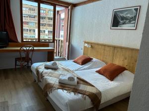 two beds in a room with a desk and windows at Hôtel Valfréjus Vacances in Valfréjus +77 photos