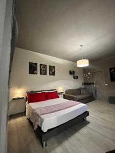 1 dormitorio con cama con almohadas rojas y sofá en Sleep & Fly BGY Airport-Station-Center, en Bérgamo