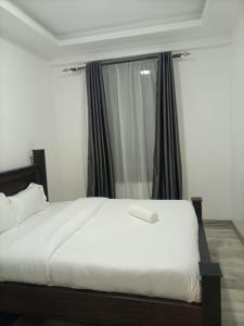 a bedroom with a white bed and a window at Pine 2 bedroom apartment with a pool in Nanyuki +11 photos