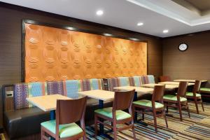 a dining room with tables and chairs and a clock at Fairfield Inn by Marriott Lexington Park Patuxent River Naval Air Station in Lexington Park