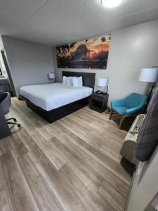 a bedroom with a bed and a blue chair at Days Inn by Wyndham Charleston WV in Charleston
