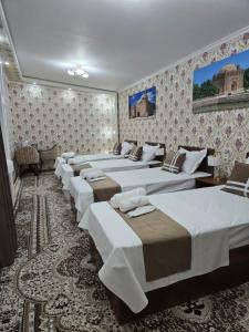 a row of beds in a room with wallpaper at Shukran hotel in Bukhara