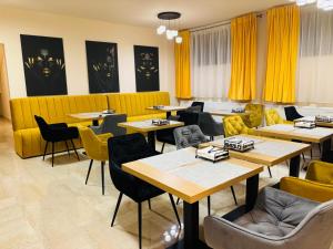 a restaurant with tables and chairs and yellow curtains at Mellis Boutique in Cluj-Napoca