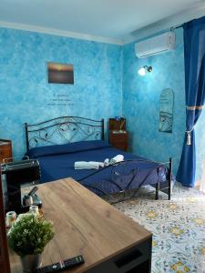 a bedroom with a bed with blue walls and a table at Casa Vacanze Central Cincotta in Lipari