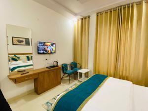 a hotel room with a bed and a desk and a television at RY Luxuries, 300m from Golden Temple in Amritsar
