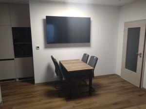 a dining room table with chairs and a flat screen tv at Apartman terasa v Dole in Černý Dŭl