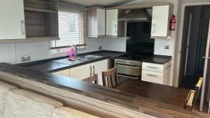 a kitchen with white cabinets and a wooden table at Sunflower 62 Braunton in Ashford