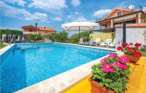 a swimming pool with an umbrella and some flowers at 1 Bedroom Stunning Apartment In Kastel in Kaštel