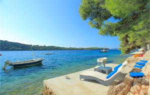 a beach with chairs and a boat in the water at Six-Bedroom Holiday Home In Karbuni in Prizba