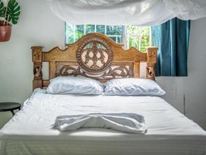 a bed with a wooden headboard and white sheets and pillows at Casa Danam in Santa Marta