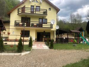 a house with a balcony and a playground at Pensiunea Alma Lepsa in Lepşa