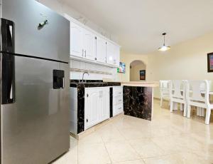 a kitchen with a stainless steel refrigerator and white cabinets at Villa DMM con piscina, jacuzzi y gran área verde en Punta Cana in Punta Cana