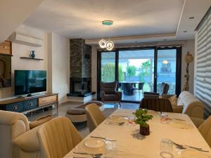 a living room with a table and chairs and a television at ÖZEL HAVUZLU Müstakil LÜKS VILLA in Kusadası