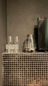 a counter with glasses and a tea pot and a tv at City Apartments Trier-Karl-Marx Suite 1 in Trier