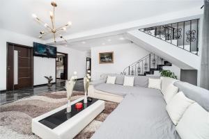 a living room with a white couch and stairs at Villa cu 4 dormitoare de 3 stele Timiș, perfectă pentru familii sau grupuri in Utvin
