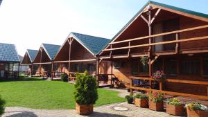 a row of wooden cottages with plants in pots at Domki i apartamenty Morska Dolina Ustronie Morskie in Ustronie Morskie