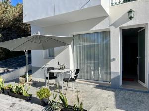 a patio with an umbrella and a table and chairs at Casa Caloura Passion Deluxe Accommodation & Spa in Lagoa
