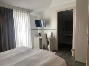 una camera da letto con un letto, una scrivania e una finestra di Hotel Dogana a Sirmione