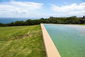 a large pool of water next to a grass field at The Stargazing Cube - Misty Mountain Reserve in Stormsrivier