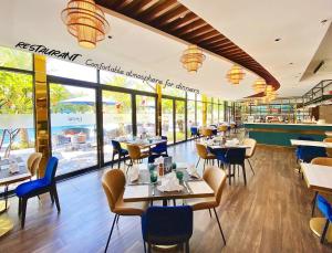 un restaurant avec des tables, des chaises et des fenêtres dans l'établissement Luxstay apartment Swimming pools and private beach, à Dien Ban